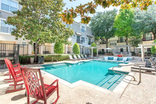 Outdoor swimming pool with lounge chairs and red rocking chairs.