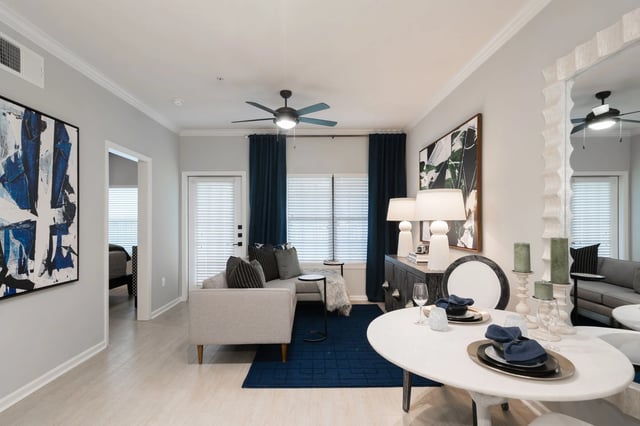 Living and dining area with modern furnishings, neutral walls, and blue accents.