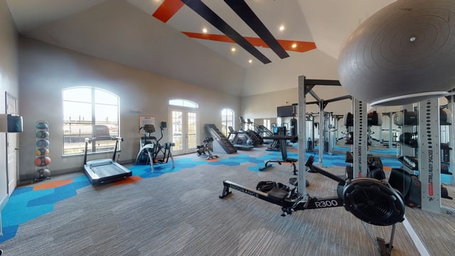 Fitness center with treadmills, ellipticals, rowing machine, free weights and a punching bag.