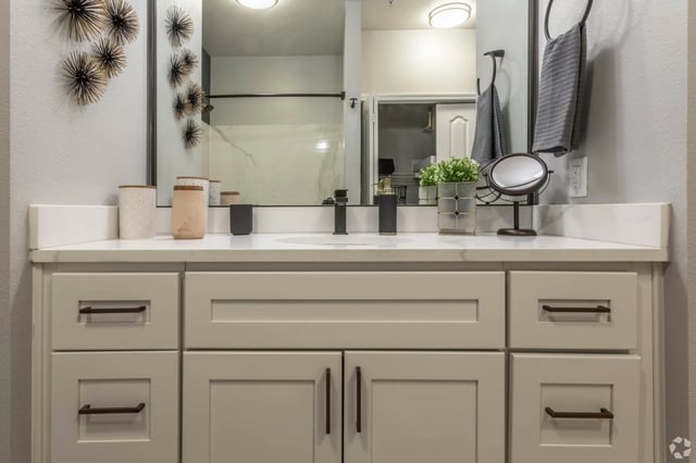 Modern bathroom vanity with a white countertop, black faucet, and decorative accents.