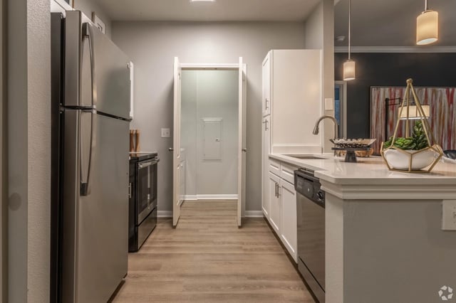 Modern kitchen with stainless steel appliances, white cabinets, and quartz countertops.