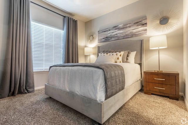 A plush bedroom with a queen-sized bed, bedside table, and window.