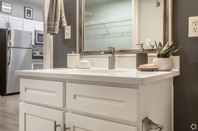 Modern bathroom vanity with white quartz countertop, silver faucet, and decorative soap dispenser.