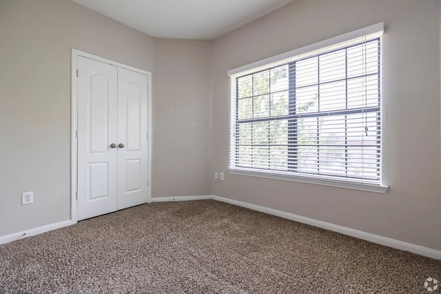 Empty bedroom with closet and large window.