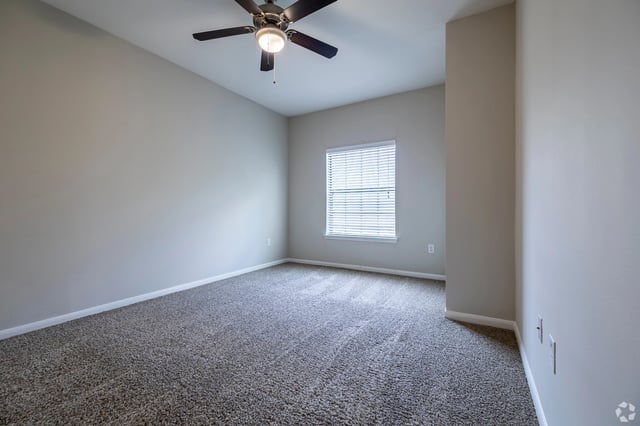 Empty bedroom with carpet and a ceiling fan.