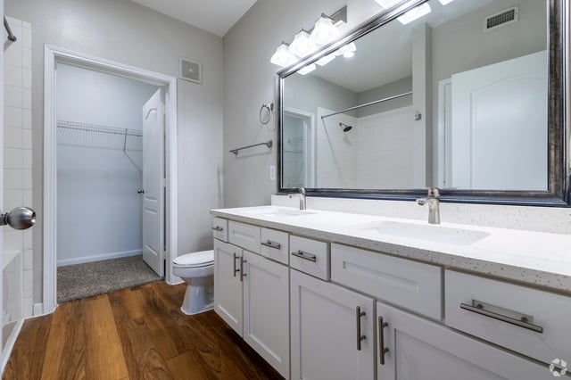 Modern bathroom with double vanity, large mirror, and walk-in closet.