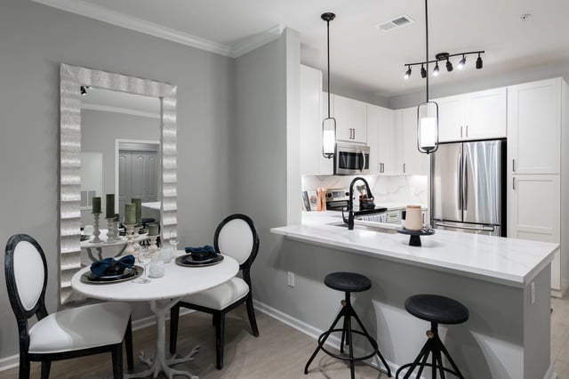 Modern kitchen with white cabinets, stainless steel appliances, and a breakfast bar with stools.