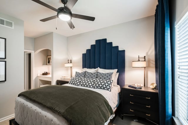 Bedroom with a king-size bed, navy blue headboard, and patterned pillows.
