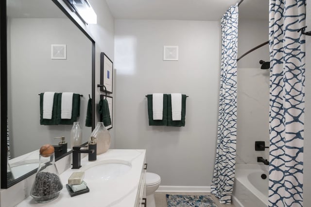 Modern bathroom with a white vanity, black faucet, and large mirror.