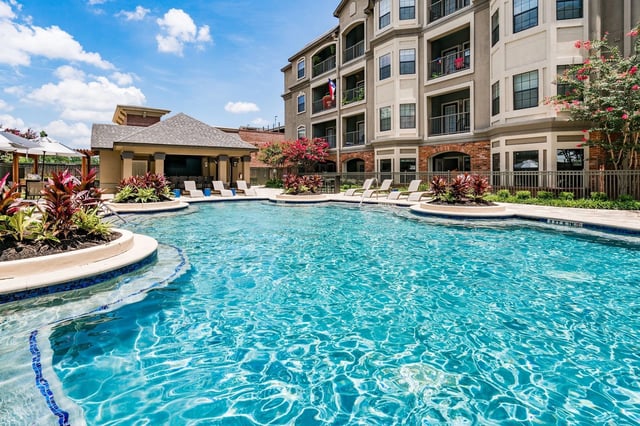 Sparkling blue swimming pool with lounge chairs and cabana.