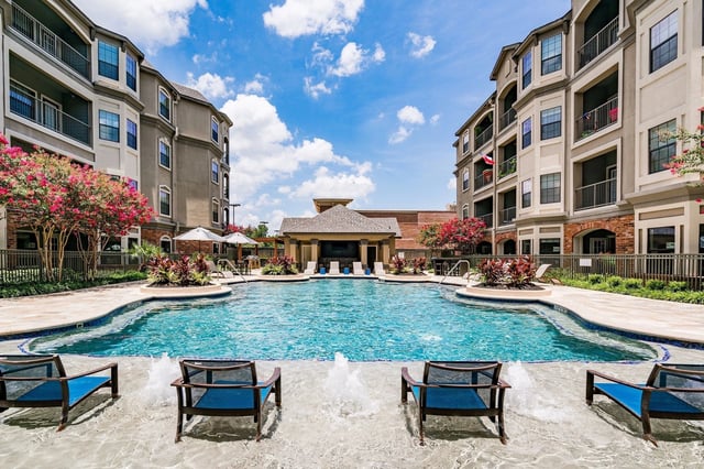 Resort-style swimming pool with loungers and a cabana at a multifamily property.