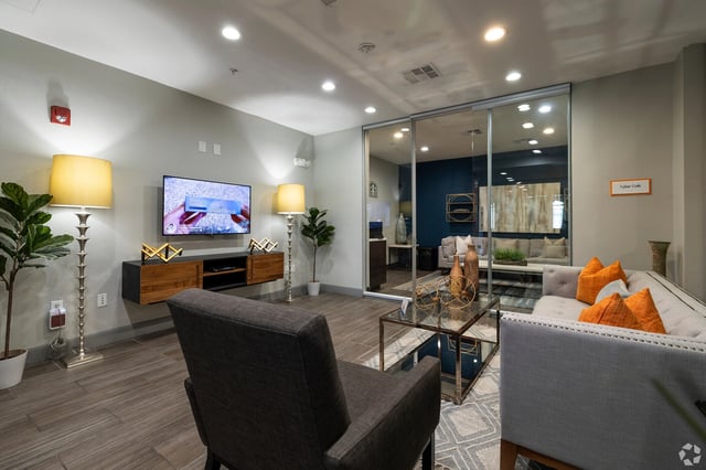 Modern lounge area with gray armchair, sofa, coffee table, and TV.
