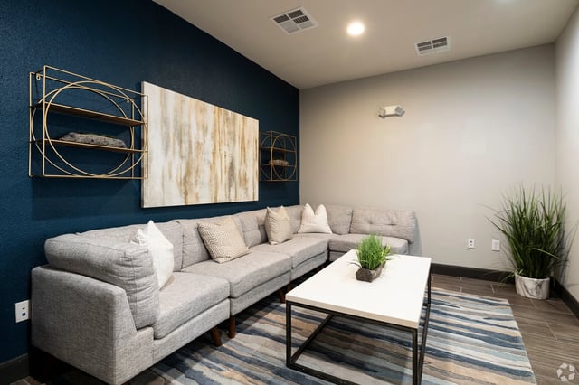 Modern lounge area with a large sectional sofa, coffee table, and abstract art.