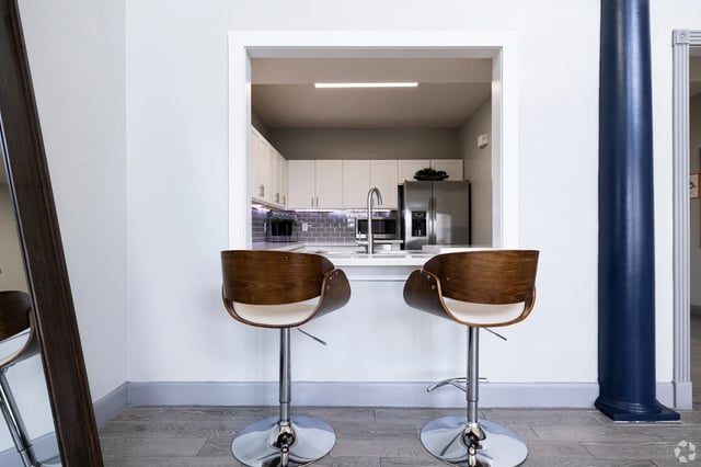 View into a modern kitchen from a dining area with two bar stools.