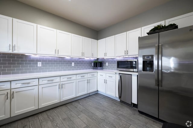 Modern kitchen with white cabinets, stainless steel appliances, and grey subway tile backsplash.