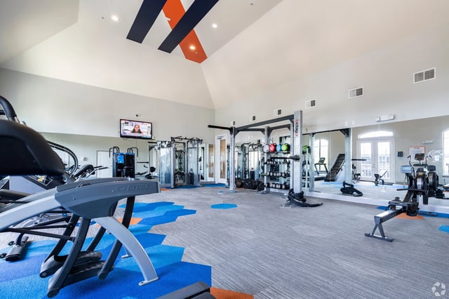 A spacious and well-equipped fitness center with cardio machines, weight racks, and mirrors.