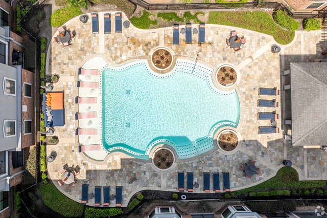Aerial view of a resort-style swimming pool with lounge chairs and tables.