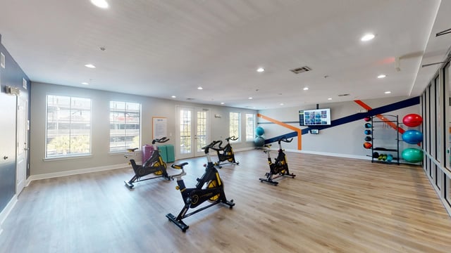 Spin bikes and exercise equipment in a well-lit fitness center.