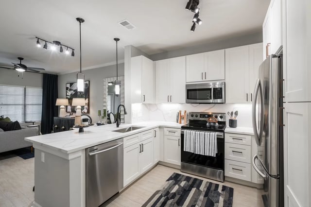 Modern kitchen with white cabinets, quartz countertops, stainless steel appliances, and island.