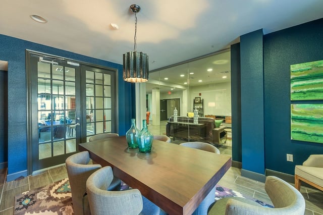 Table and chairs in a lounge area with glass walls looking into a seating area.