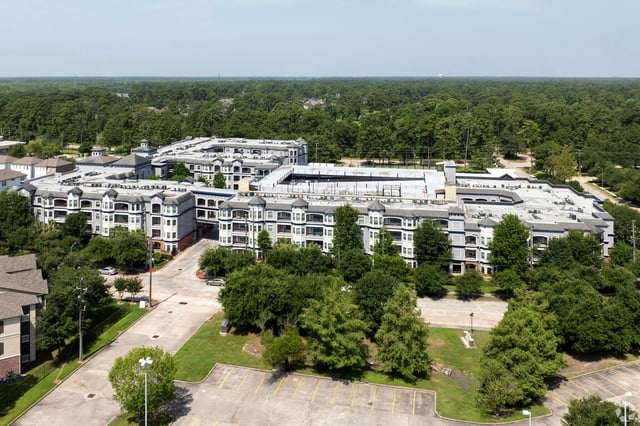 Aerial view of a large apartment complex surrounded by trees.