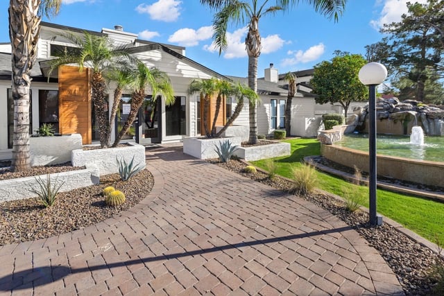 Property entrance with courtyard, fountain, and lush landscaping.