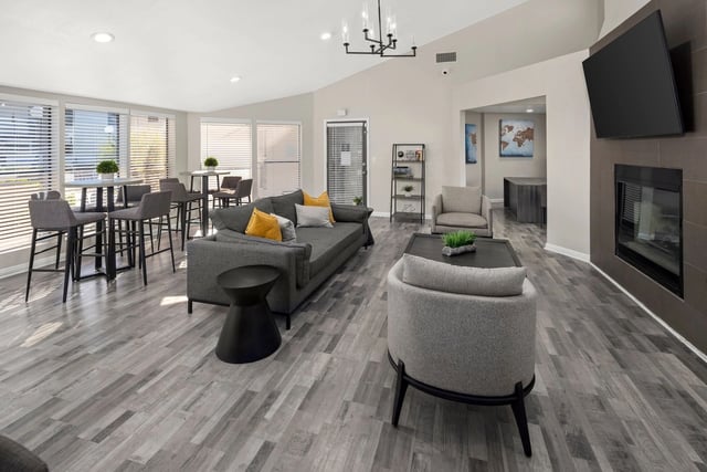 Modern community lounge area with comfortable seating, high-top tables, and a fireplace.