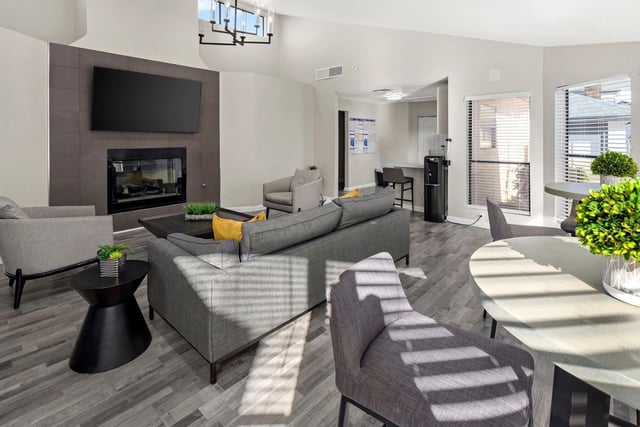 Modern community lounge with fireplace, TV, seating, and kitchen area.