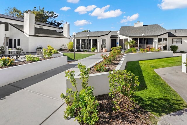 Apartment building exterior with manicured landscaping and outdoor seating.
