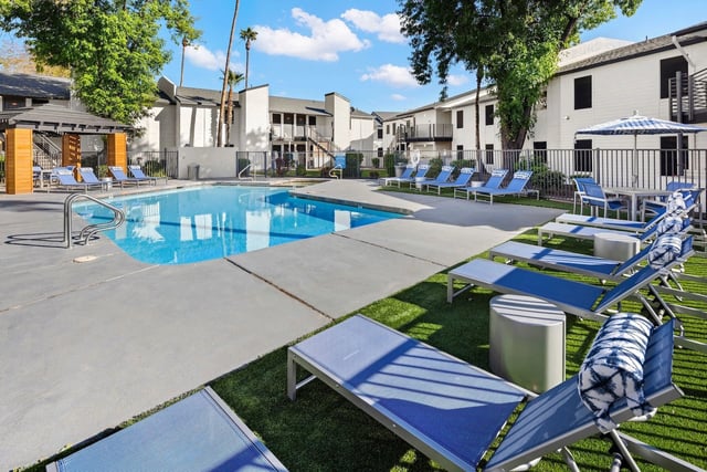 Resort-style pool with lounge chairs and umbrellas