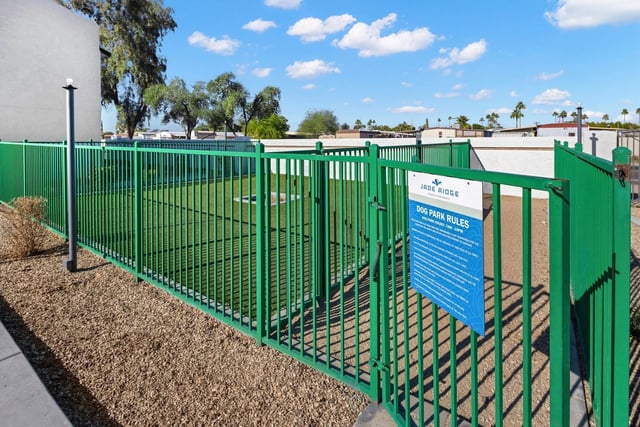 Jade Ridge apartments dog park with green fencing and a rules sign.