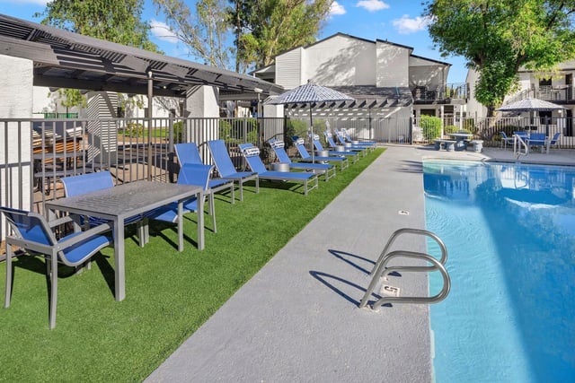 Resort-style swimming pool with lounge chairs and an outdoor dining area.