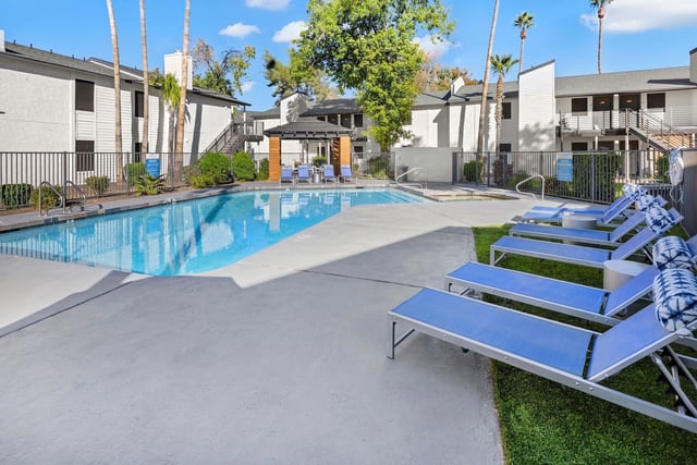 Outdoor swimming pool with lounge chairs and a covered seating area.