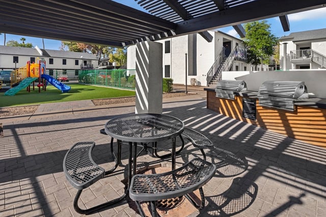 Outdoor seating area with grills and playground in the background