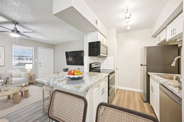 Modern kitchen and living room with island and stainless steel appliances.