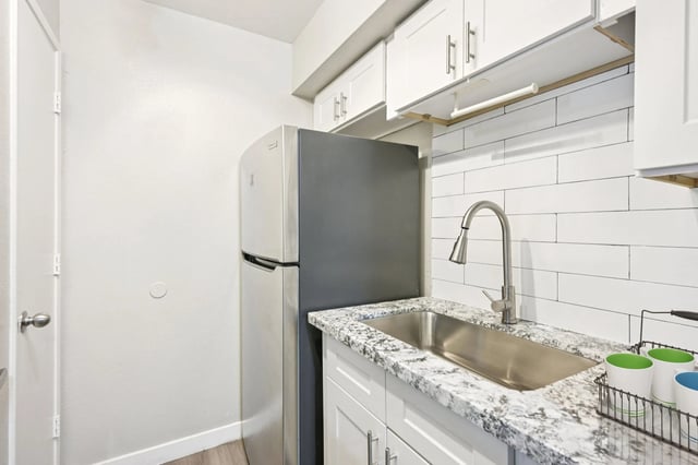 Kitchen featuring a stainless steel refrigerator, granite countertops, and a deep sink with a pull-down faucet.