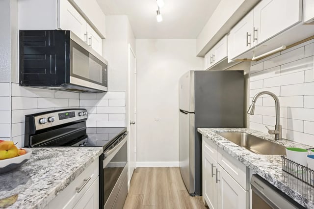 Modern kitchen with stainless steel appliances and white cabinets.
