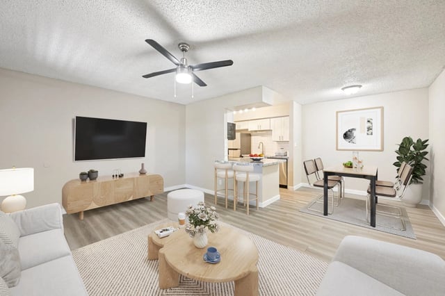 Living room with a TV, sofa, coffee table, and dining area leading to a kitchen.