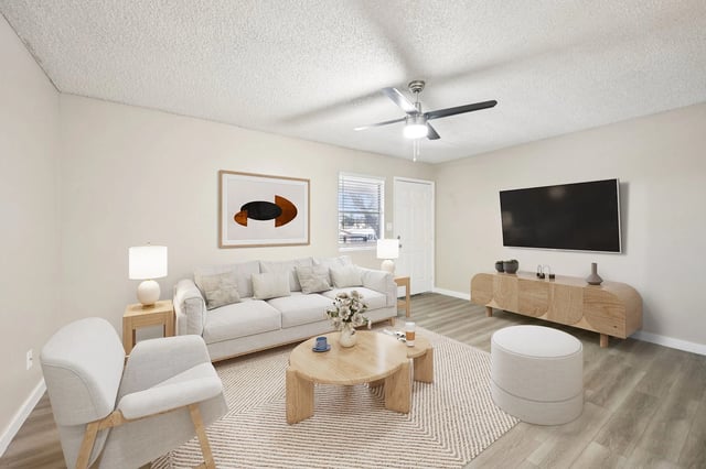 A bright living room with a sofa, coffee table, and TV.
