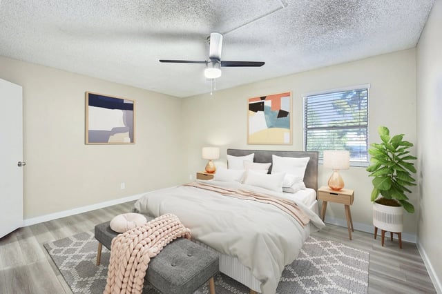 King size bed with white linens, flanked by nightstands with lamps, in a neutrally decorated bedroom.