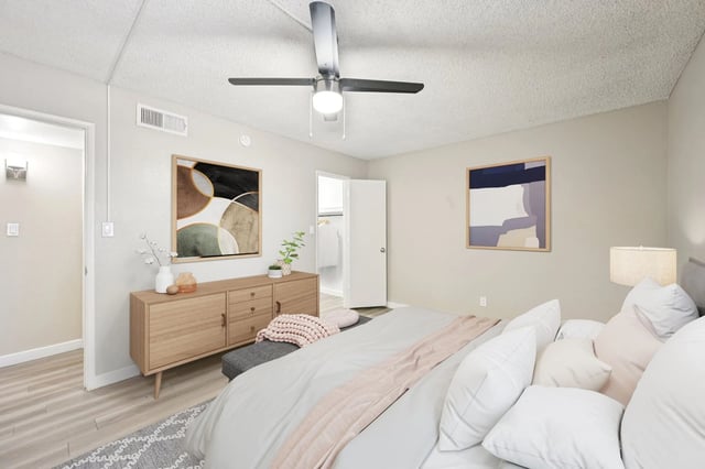 Bedroom with a king-size bed, dresser, ceiling fan, and abstract art.