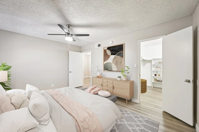 Bedroom with a king-size bed, dresser, ceiling fan, and walk-in closet.