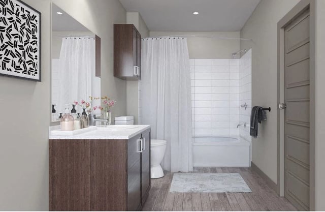 Modern bathroom with vanity, toilet, and bathtub with shower.