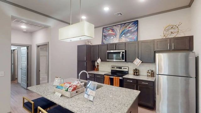 Modern kitchen with dark wood cabinets, stainless steel appliances, and a granite island.