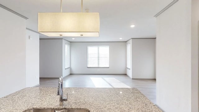 Kitchen counter with sink and faucet, open to a spacious living area with large windows.