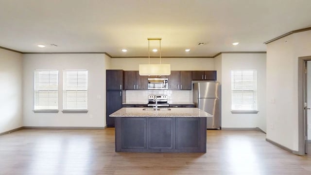 Modern kitchen with a large island, stainless steel appliances, and dark cabinetry.
