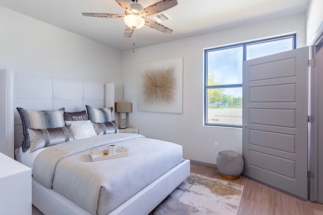 A king-sized bed with plush pillows and a white duvet. A tray with a coffee cup and snacks sits on the bed.