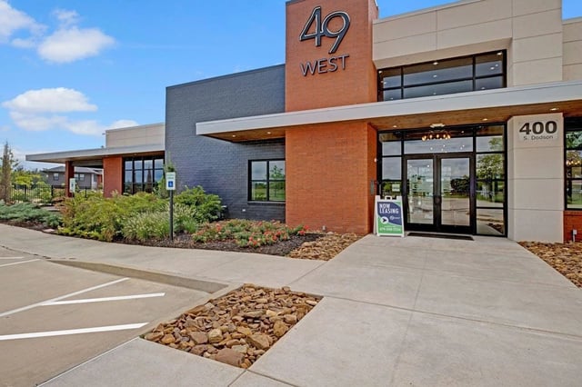 Exterior of 49 West apartment building with modern brick and dark grey facade, large glass entrance doors.