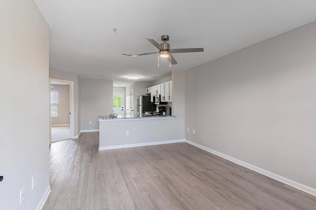 Empty living room with view of kitchen and doorway to another room.