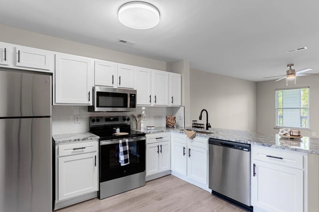 Modern kitchen with stainless steel appliances, white cabinets, and granite countertops.